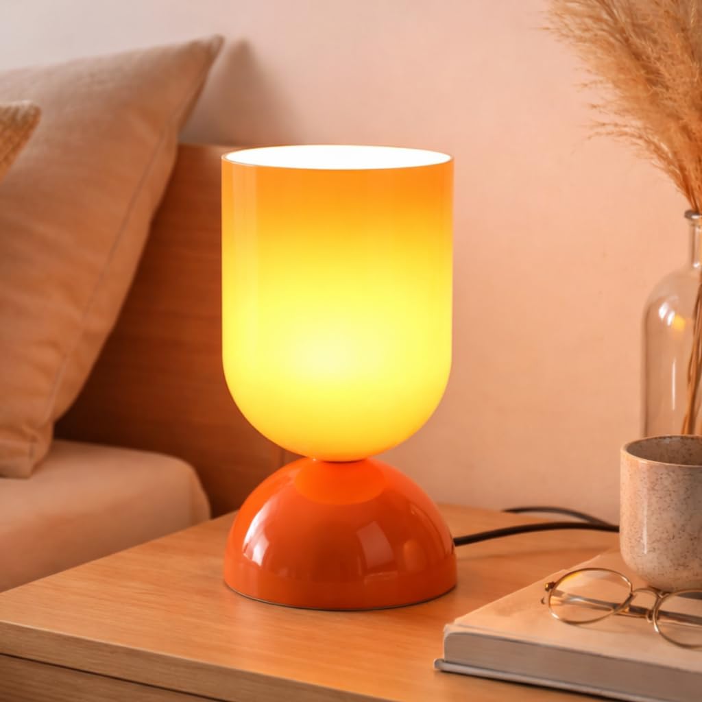 Small glowing orange glass table lamp with a glossy dome base